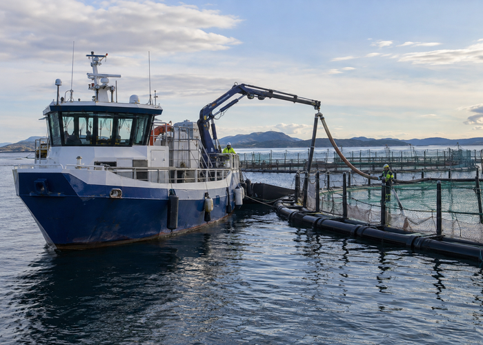 real aquaculture service vessel beside floating fish-farm net pens with unbranded physical 3D LiDAR sensors monitoring deck clearance, feed hoses and walkways in a realistic LiDAR application scene