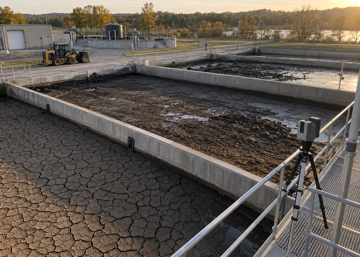 real outdoor wastewater sludge drying beds with cracked drying surfaces and a physical unbranded LiDAR scanner on a safe elevated tripod validation scene 3