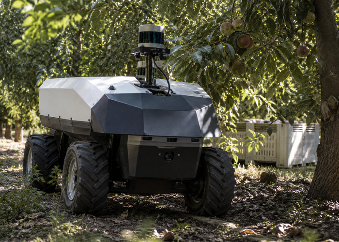 real unbranded orchard harvesting robot with physical LiDAR sensors moving between fruit trees near filled harvest bins while workers remain at a safe distance in natural sunlight validation scene 2