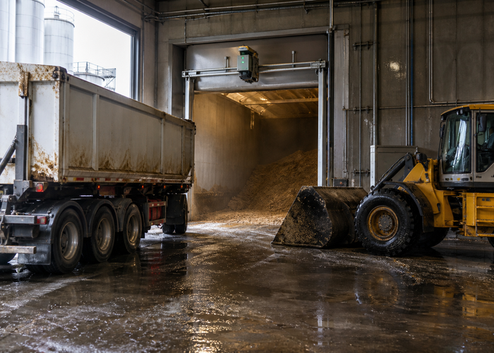 real brewery spent-grain handling bunker with wet grain piles, an unbranded fixed physical LiDAR scanner, drainage channel and loader parked outside the measurement zone validation scene 3