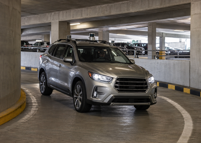 unbranded automated passenger car with physical parking LiDAR sensors moving slowly through a real multilevel parking garage with ramps, wheel stops and a safely separated pedestrian handover area validation scene 2