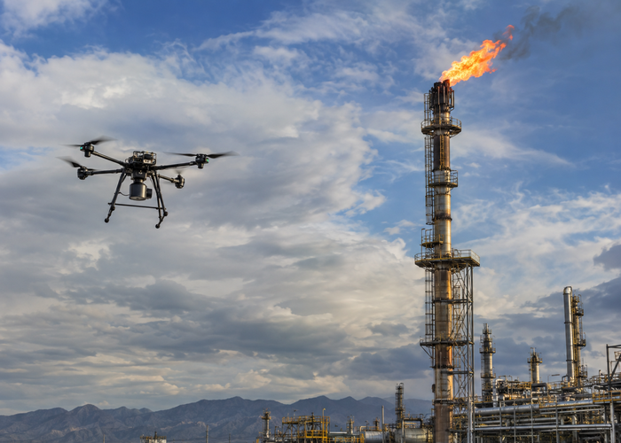 real industrial flare stack inspection with an unbranded multirotor drone carrying visible physical LiDAR at a safe stand-off distance in a realistic LiDAR application scene