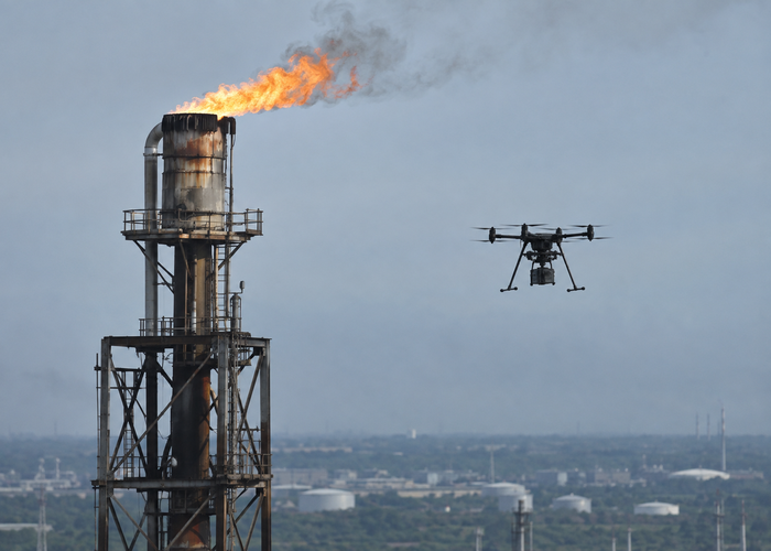 real industrial flare stack inspection with an unbranded multirotor drone carrying visible physical LiDAR at a safe stand-off distance validation scene 3