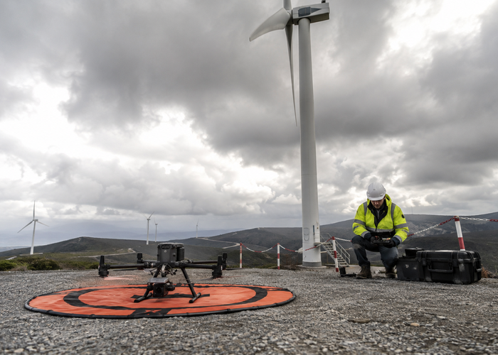 real unbranded inspection drone with a physical LiDAR sensor holding position beside a wind-turbine nacelle and blade root in natural daylight validation scene 3