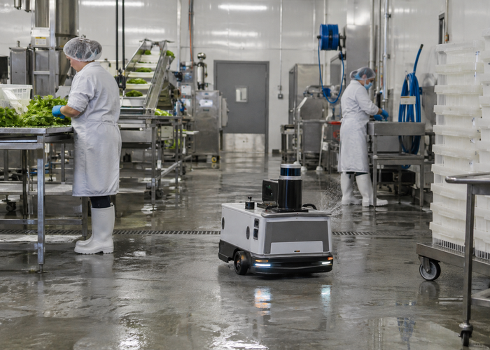 real food-processing washdown room with stainless equipment and an unbranded mobile robot carrying visible physical LiDAR during sanitation validation in a realistic LiDAR application scene