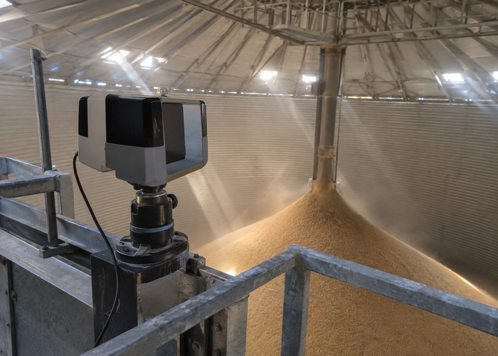 real grain silo interior inspection context with a visible unbranded physical LiDAR scanner safely mounted near roof access above grain surface in a realistic LiDAR application scene